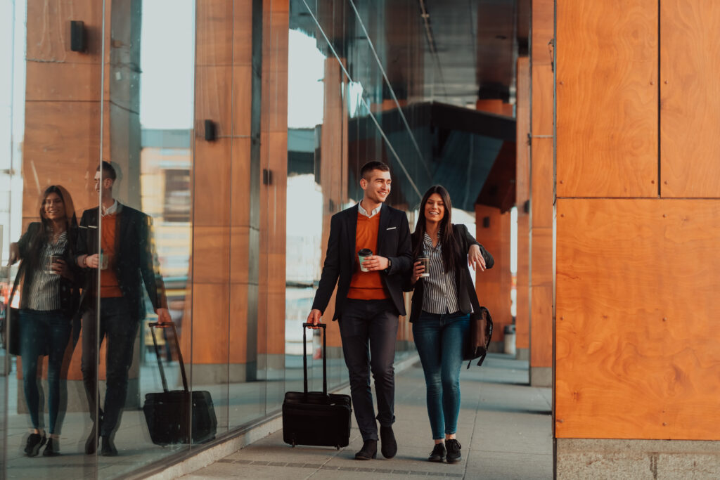 businessman with a suitcase walks around town drinking coffee with his colleague
